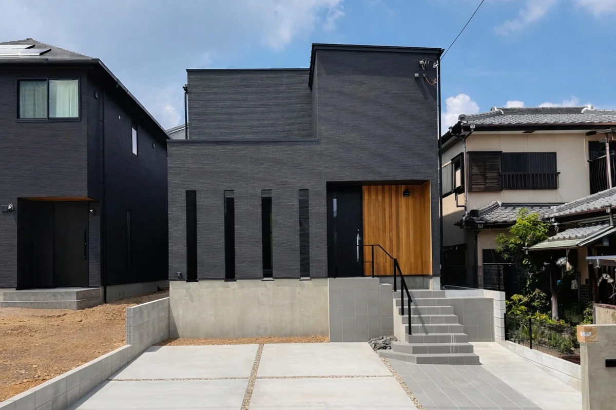黒い外壁に縦長の窓と木の玄関を組み合わせた住まい
